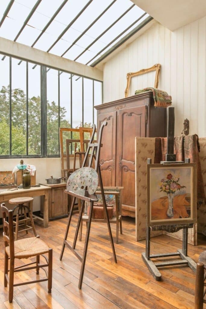 A recreated artist’s studio with a vintage easel, paint-stained palette, wooden furniture, and a vase of flowers painting—evoking the workspaces of famous residents of Montmartre such as Valadon and Utrillo.