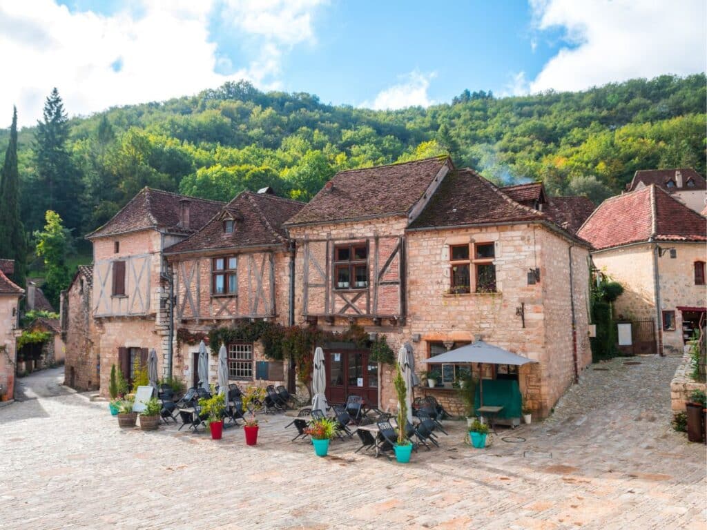 The village of Saint-Cirq-Lapopie, with half-timbered stone houses and cobbled squares surrounded by forested hills, offering a fairy-tale stop on a road trip through France.