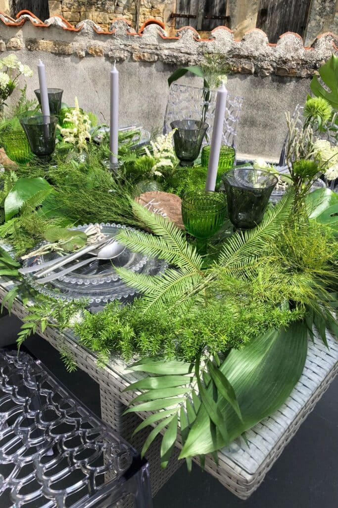 The perfect blend of rustic charm and modern elegance, featuring a greenery-filled tablescape with crystal-clear chairs and a stone-walled backdrop. Personalized details, like handwritten leaf place cards, make it extra special.